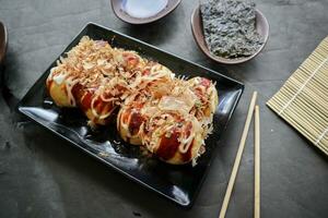 Takoyaki ist ein japanisch Essen, gemacht von Weizen Mehl Teig, Tintenfisch Fleisch, oder andere Füllungen, serviert mit Soße, Mayonnaise und Belag im das bilden von katsuobushi oder Holz Fisch Rasuren. foto
