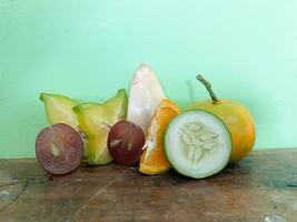 Stücke von Frucht. verschiedene Stücke von Star Frucht, Trauben, Orangen, Gurken, salak Obst auf Tabelle foto