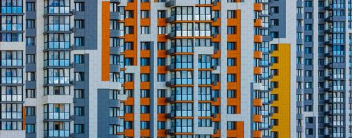 Vollbild Aussicht von frisch gebaut hoch erhebt euch Wohnung Gebäude im Weiss, grau und Orange Farben foto