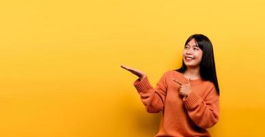 asiatisches Mädchen, das ein orangefarbenes Freizeitkleid auf gelbem Hintergrund trägt foto