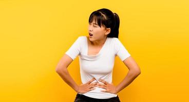asiatische Frau mit starken Bauchschmerzen allein auf einem gelben