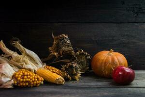 Herbst Ernte Konzept mit Mais quetschen Sonnenblumen und Äpfel auf rustikal Hintergrund foto