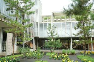 Solo, Indonesien - - Juni 10, 2022 Gebäude Konstruktion, Landschaft Gebäude im ein Blume Garten mit Blau Glas Fenster und Tanne Bäume foto