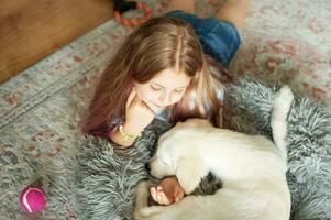 wenig Mädchen spielen mit ein golden Retriever Hündchen beim heim. foto