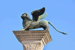 ein Statue von ein Löwe mit Flügel auf oben von ein Säule foto