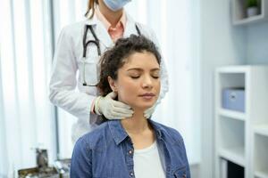 Endokrinologe Prüfung Kehle von jung Frau im Klinik. Frauen mit Schilddrüse Drüse Prüfung . Endokrinologie, Hormone und Behandlung. Entzündung von das wund Kehle foto