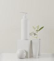 Sahne- oder Parfümpumpflasche auf weißem Hintergrund und Blumenvase foto