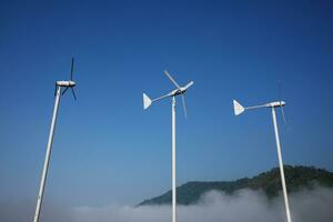 Jahrgang Windmühlen Flugzeug gestalten zum elektrisch Leistung Produktion mit nebelig und Blau Himmel auf das Hügel und Berg foto