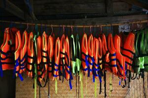 Orange Leben Weste Jacken hängend auf Gestell draussen zum Sicherheit und Schutz während mit im wie Schwimmen beim das Meer. foto