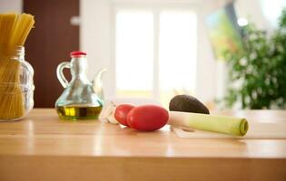 gesund organisch roh Gemüse zum Salat auf das Tabelle in der Nähe von ein Ölkanne mit frisch extra Jungfrau Öl auf das Küche Tabelle foto