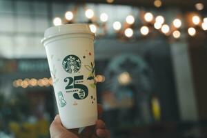 Bangkok, Thailand - - Oktober 17, 2023 Mann halten wiederverwendbar Tasse, 25 Jubiläum, Starbucks Thailand, erhalten 1 frei. limitierte Auflage, beschränkte Auflage foto