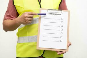 Mitarbeiter halten leer Überprüfung auf Sicherheit Checkliste form. Hand von Mitarbeiter ist mit das Sicherheit Checkliste Blatt zu überprüfen Arbeiten Bedingung im isoliert Hintergrund. foto