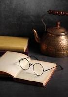 Alte Bücher und Gläser öffnen sich auf dem Tisch in der Bibliothek foto