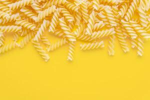 verstreut roh Pasta Fusilli isoliert auf Gelb Hintergrund. Essen Hintergrund, Italienisch Küche foto