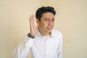 jung indonesisch lockig Mann tragen Weiß Kleider mit können nicht hören Pose. foto