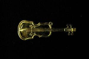 ein Gold Ton Violine Charme auf ein schwarz Hintergrund foto