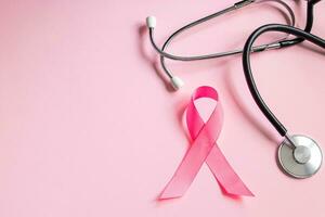 Brustkrebs-Aufklärungsmonat. Rosa Schleife und Stethoskop auf farbigem Hintergrund. Frauengesundheitskonzept. Symbol des Kampfes gegen die Onkologie. foto