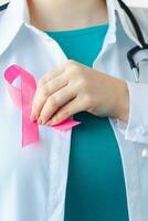 Ärztin in medizinischer weißer Uniform mit rosa Schleife. Brustkrebs-Aufklärungsmonat. Frauengesundheitskonzept. Symbol der Hoffnung und Unterstützung. foto