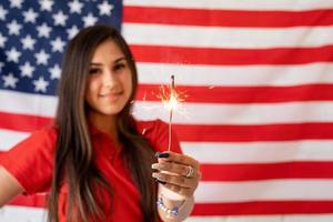 schöne frau, die eine wunderkerze auf dem hintergrund der usa-flagge hält foto