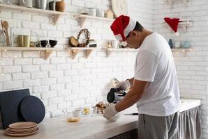 Mann mit Weihnachtsmütze macht Baiser auf weißem Holztisch foto