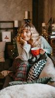 junge Frau mit Tasse Tee im gemütlichen Weihnachtsinterieur foto