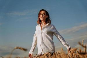 glückliche junge Frau in einem weißen Hemd in einem Weizenfeld. sonniger Tag.