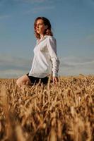 glückliche junge Frau in einem weißen Hemd in einem Weizenfeld. sonniger Tag.