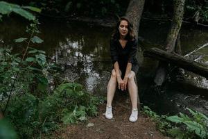 Frau in schwarzer Kleidung in einem dunklen Nadelwald. Verfolgung und Reise foto