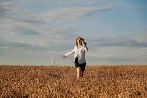 Frau läuft an einem Sommertag in einem Weizenfeld. Glück und Freude Konzept foto