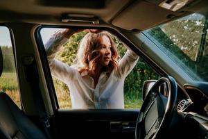 Frau im Autofenster. Ausflüge aus der Stadt. Reise- und Freudenkonzept foto