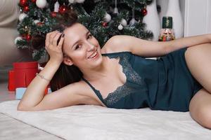 sexy junges Mädchen in Unterwäsche liegt in der Nähe von Geschenken. Weihnachtsinterieur foto