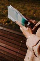 Frau in einem Herbstmantel hält ein Buch. Herbstpark foto