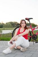 Mädchen sitzt neben ihrem Fahrrad im Park und hört Musik foto