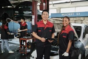 Porträt von Fachmann Mechaniker Supervisor Partner aussehen beim Kamera, Arbeit beim Auto Bedienung Garage, glücklich Instandhaltung Arbeitsplätze, prüfen und Reparatur Ingenieur Besetzung im Automobil Industrie Geschäft. foto