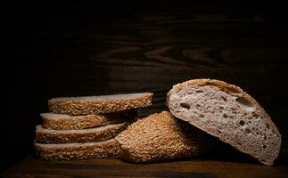 Schnitt Laib von Brot und Stücke von Brot auf ein hölzern Hintergrund. Ciabatta Brot. foto