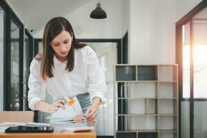 Geschäftsfrau Arbeiten im Stapel von Papier Dateien zum suchen und Überprüfung unvollendet dokumentieren erreicht auf Ordner Papiere beim beschäftigt Arbeit Schreibtisch Büro foto