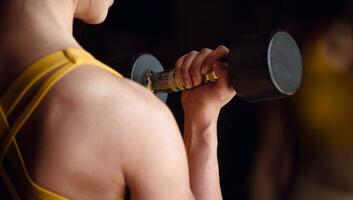 jung weiblich tun Übung mit Hantel im Vorderseite von ein Spiegel im das Fitnessstudio. foto