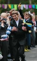 ukraine, kiev 2008- der Oberschüler trägt einen Erstklässler, der an der Glocke läutet und über den Beginn des neuen Schuljahres informiert