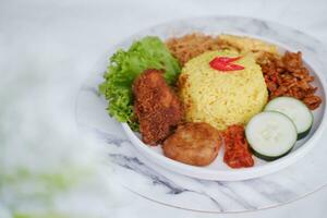 indonesisch Stil Gelb Reis mit Hähnchen und Seite Geschirr im Weiß Teller foto