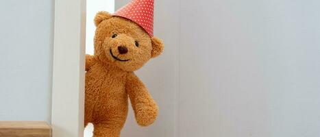 süß braun Teddy Bär Spielzeug schleichen hinter das Tür und Überraschung zu gratulieren das Besondere Tag Urlaub Feste. Spiel Kind, Tag Pflege, Willkommen, Kind Tag, schüchtern Kindheit, Party lustig, ausgestopft Puppe foto
