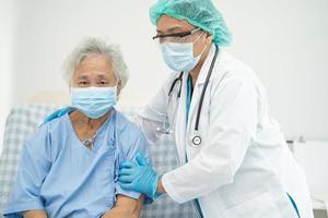 Arzt hilft asiatischen älteren Patienten, die eine Maske zum Schutz des Coronavirus tragen