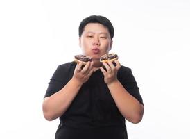 junger lustiger fetter asiatischer Mann, der Schokoladenkrapfen isst foto