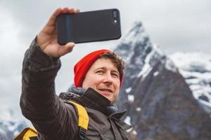 Mann macht Selfie mit Bergen im Rücken foto
