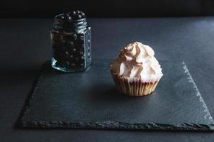 Muffin mit Johannisbeeren auf schwarzem Hintergrund.