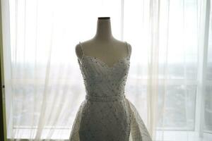 schön Weiß Hochzeit Kleid auf ein Weiß Mannequin im das Zimmer mit groß Fenster foto
