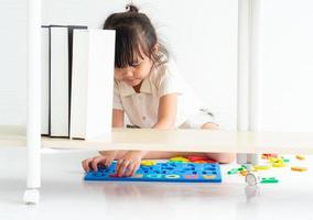 kleines Mädchen, das mit einem Alphabet-Puzzle spielt foto