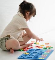 kleines Mädchen, das mit einem Alphabet-Puzzle spielt foto