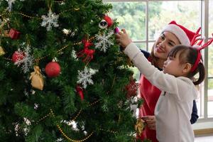 Mutter und Kind schmücken den Weihnachtsbaum foto