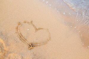 Finger Zeichnung auf das Sand. das Herz ist gemalt auf das Strand in der Nähe von das oeyan. glücklich Urlaub durch das Meer. foto