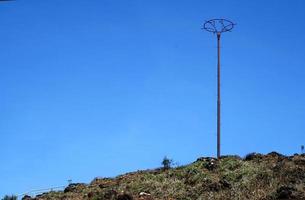 ein hoher Pfosten auf einem Hügel vor dem satten blauen Himmel foto